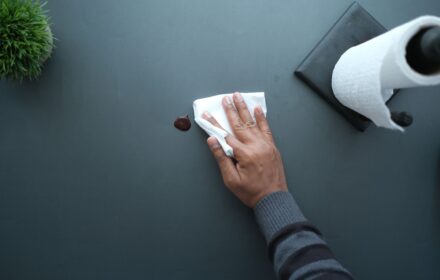 Sanitizing an office table surface during a cleaning visit