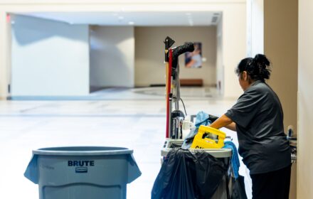 Janitorial staff with cleaning cart in commercial building hallway